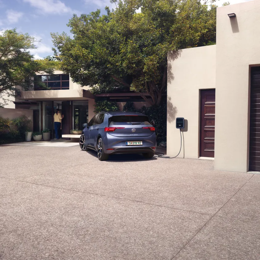 Ein blauer VW ID.3 Neo lädt an einer Wallbox vor einem Einfamilienhaus
