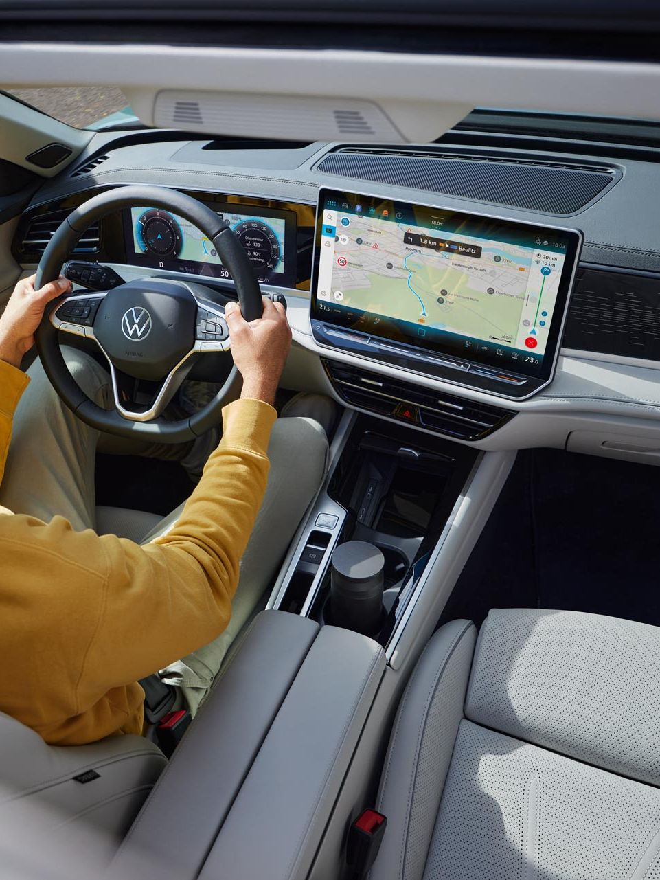 Vedere de sus prin trapa glisantă opțională deschisă a modelului VW Passat, în care un bărbat stă cu ambele mâini pe volan.