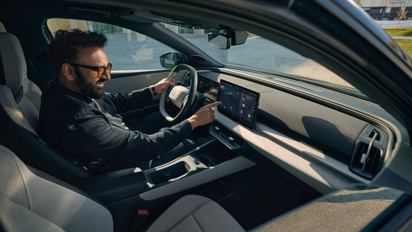 Ein Mann sitzt im VW ID. Cross und bedient das Infotainment- System.