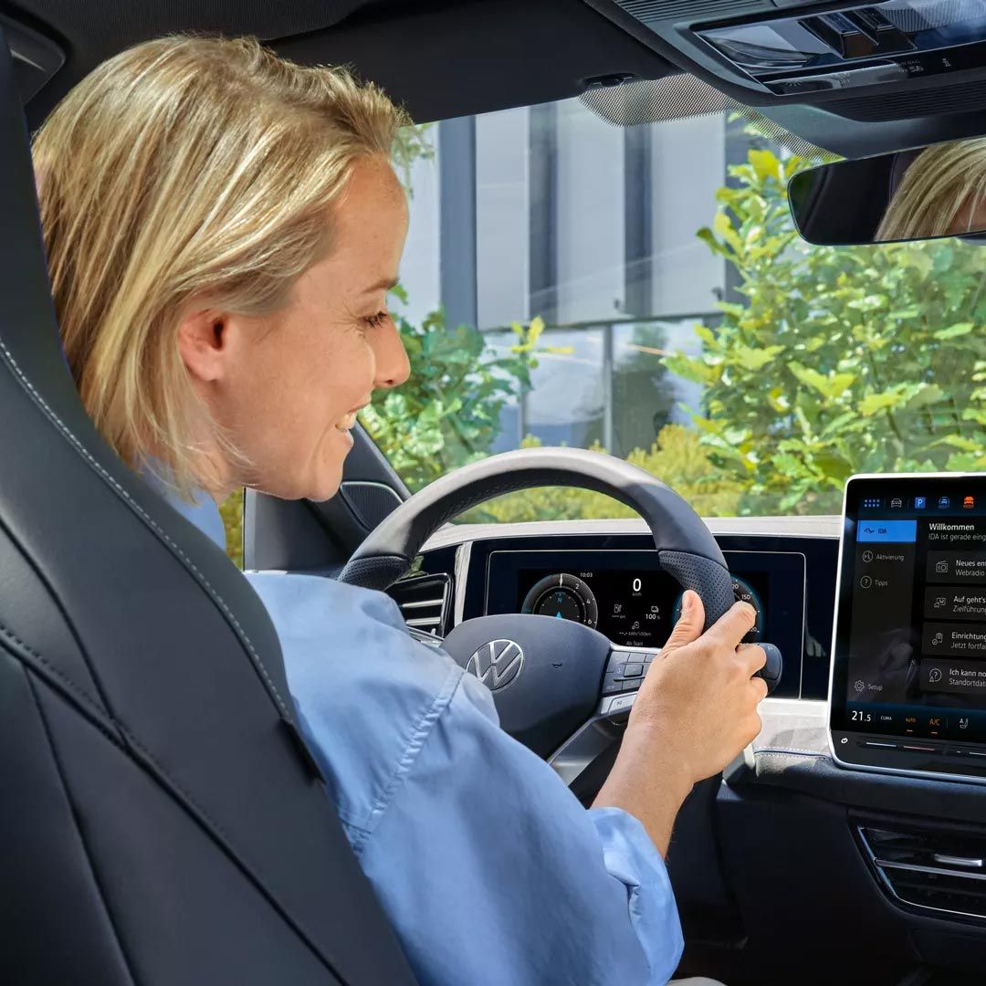Eine Frau sitzt im VW Passat und blickt auf das Infotainmentsystem