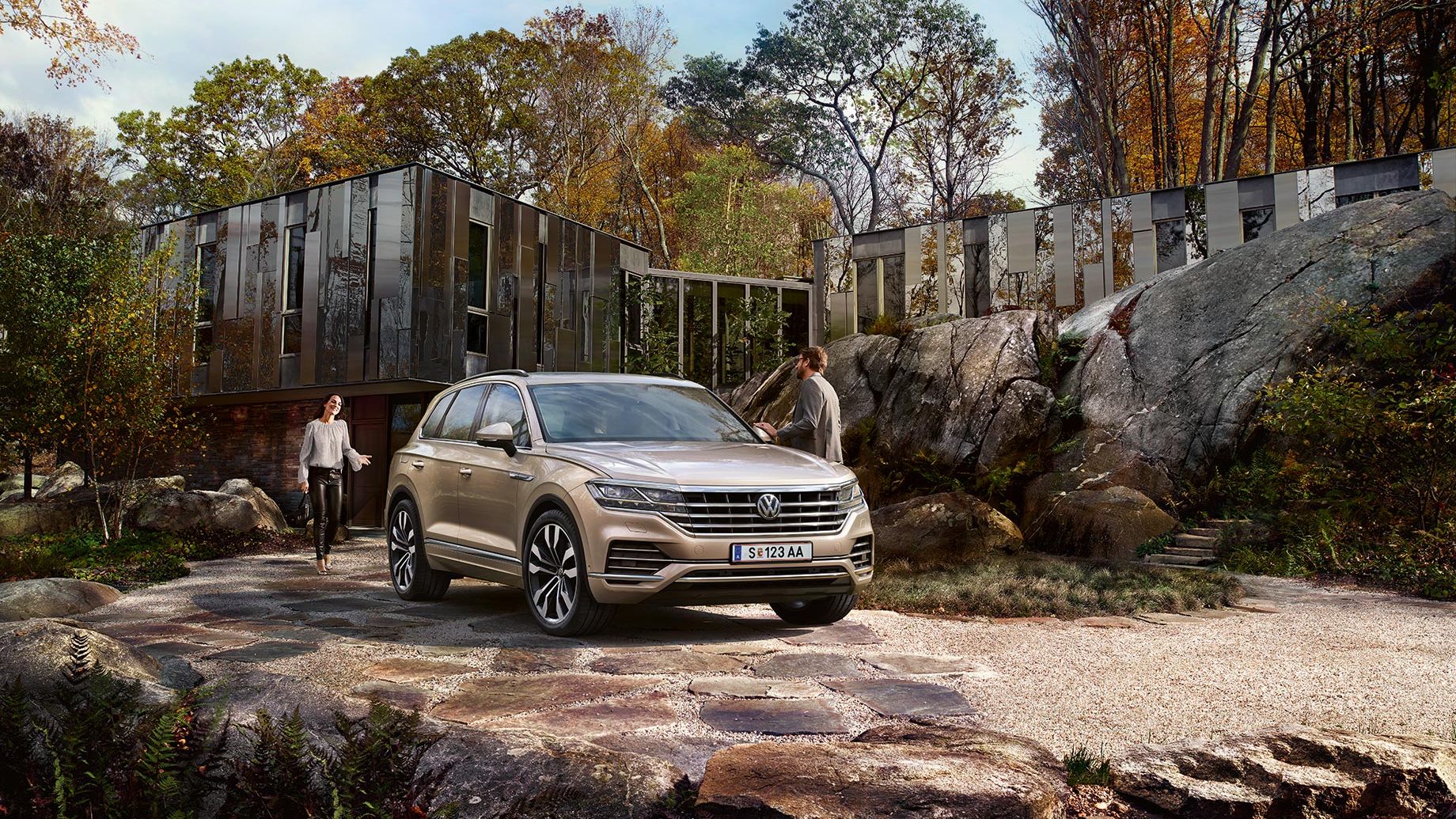 Ein VW Touareg steht geparkt in einer Einfahrt vor einem Haus, umgeben von großen Steinen 