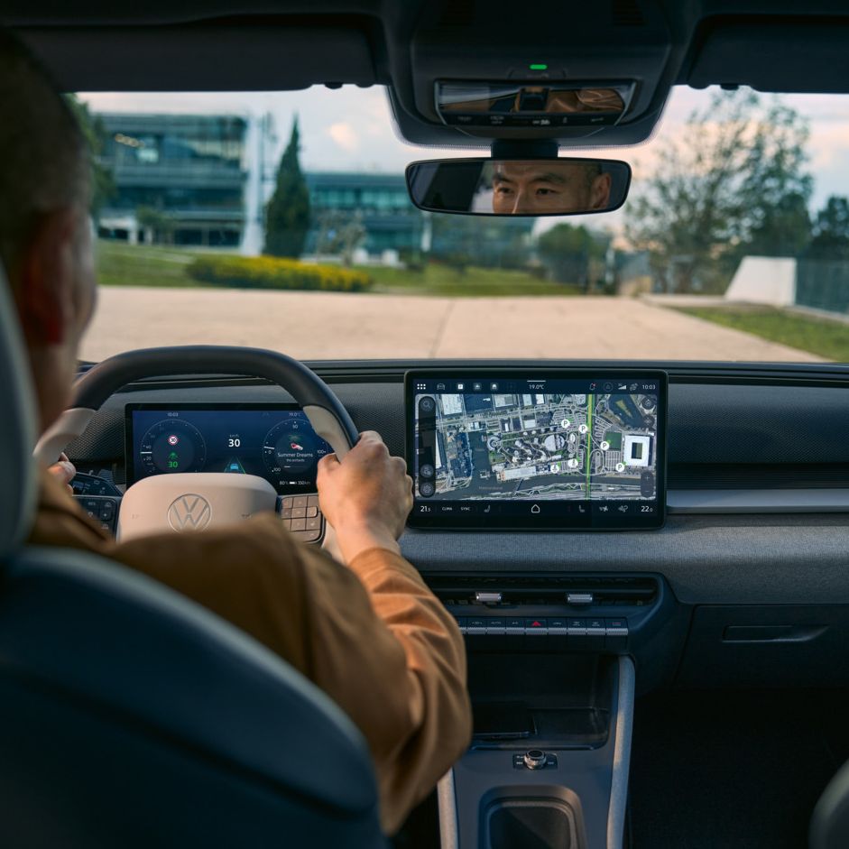 Blick vom Rücksitz in die Fahrerkabine eines VW ID. Cross mit aktiver Navigation im Infotainment-Screen.