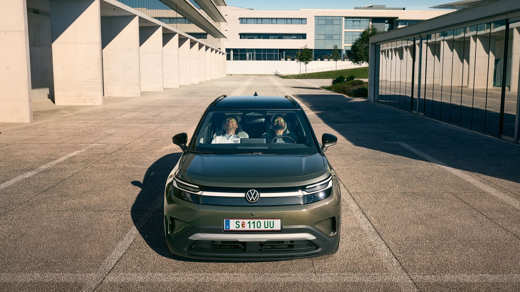 Zwei Männer sitzen zurückgelehnt und mit geschlossenen Augen auf den Vordersitzen eines VW ID.Cross, sie haben Gurkenscheiben auf den Augen.