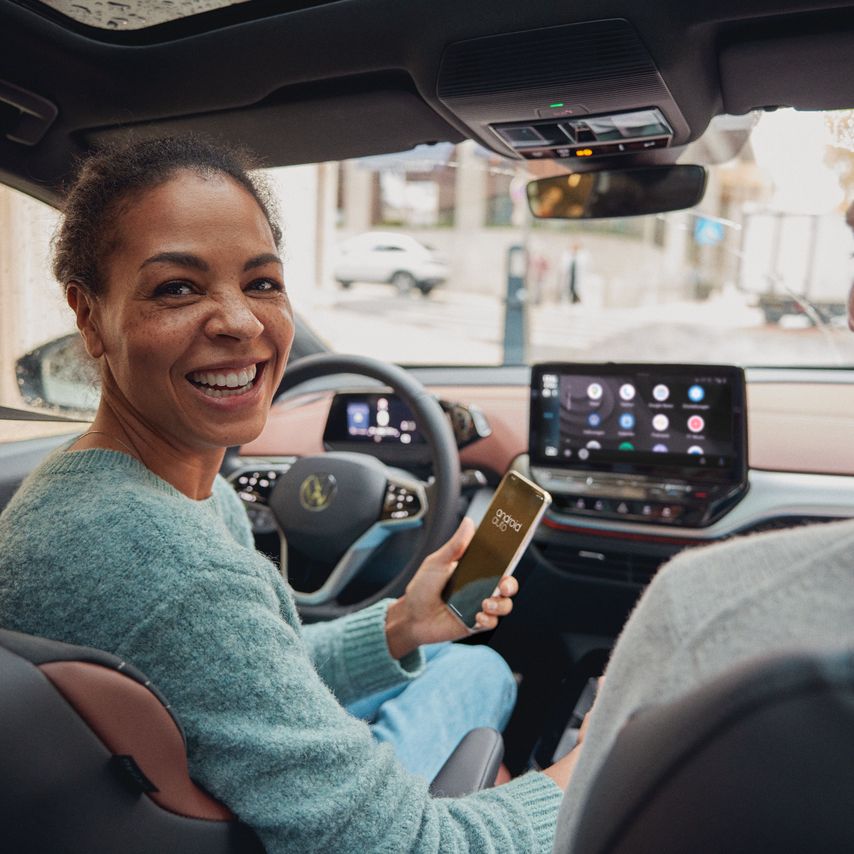 Frau bedient mit Ihrem Smartphone App Connect in Ihrem VW ID.5