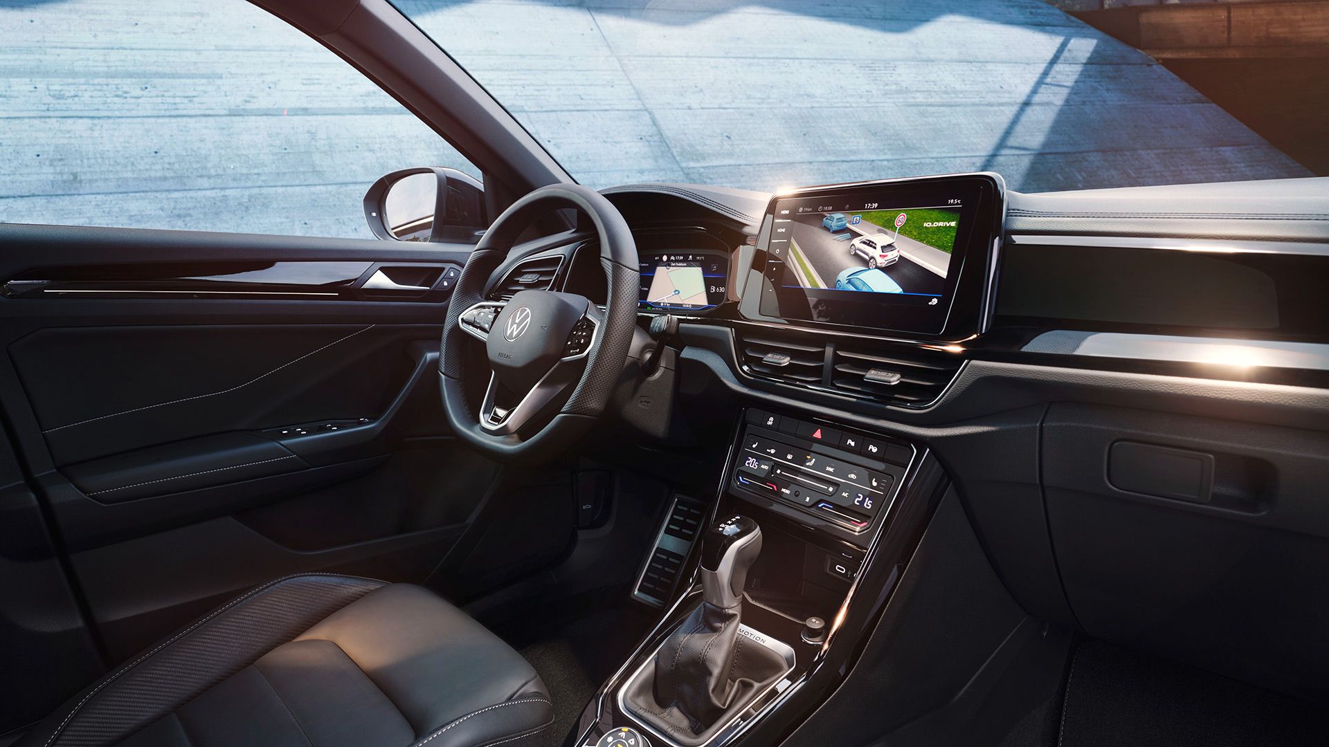 Interior VW T-Roc, perspectivă dinspre scaunul pasagerului față spre scaunul șoferului și postul de conducere cu volanul multifuncțional și sistemul Infotainment