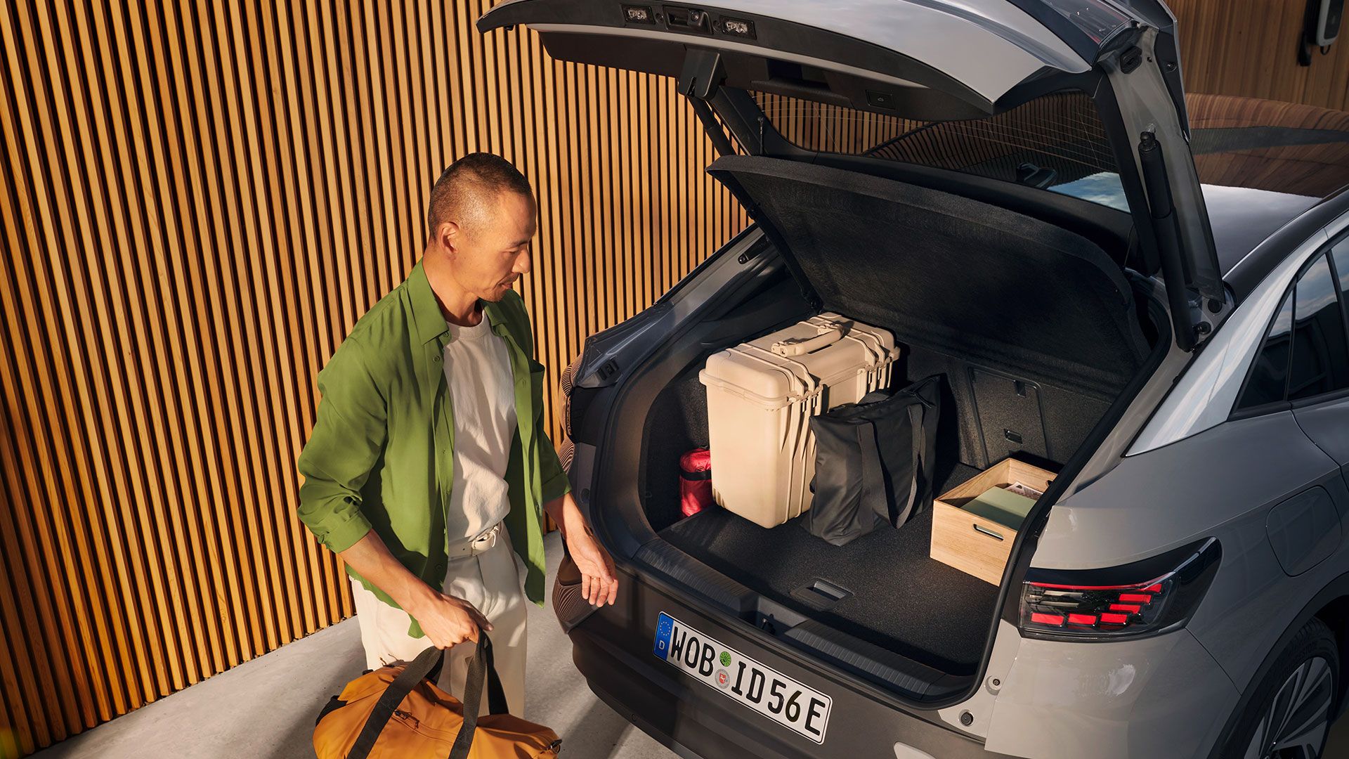 VW ID.5 cu portbagajul deschis și bagaje înăuntru, un bărbat cu o geantă în mână se află sub hayonul deschis