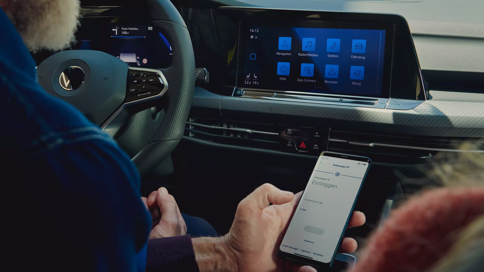 Mann hält ein Handy vor das Display im VW Golf