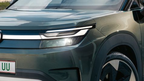 Ein grüner VW ID. Cross steht vor einem modernen Glasgebäude auf einer Betonfläche.