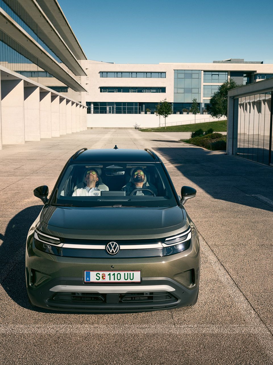 Zwei Männer sitzen zurückgelehnt und mit geschlossenen Augen auf den Vordersitzen eines VW ID.Cross, sie haben Gurkenscheiben auf den Augen.