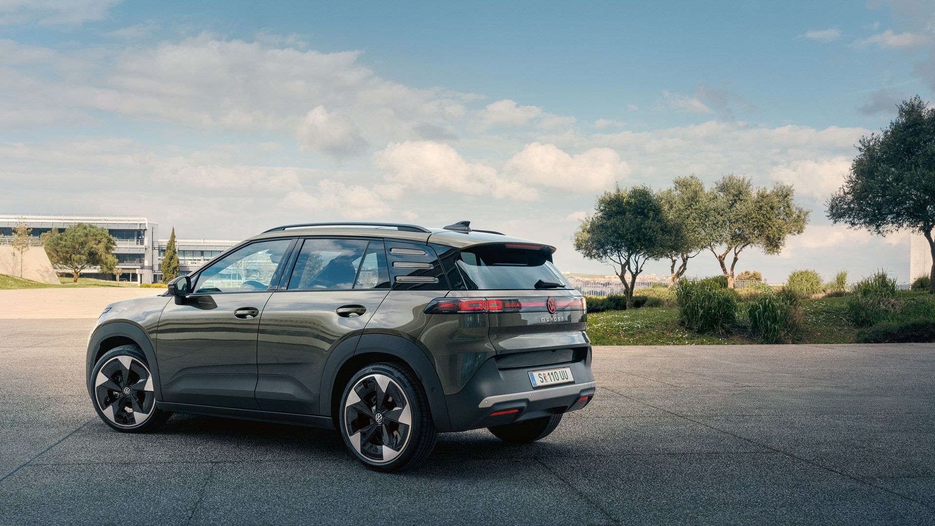 Heckansicht eines grünen VW ID. Cross, der auf einem Platz mit grünen Bäumen parkt.