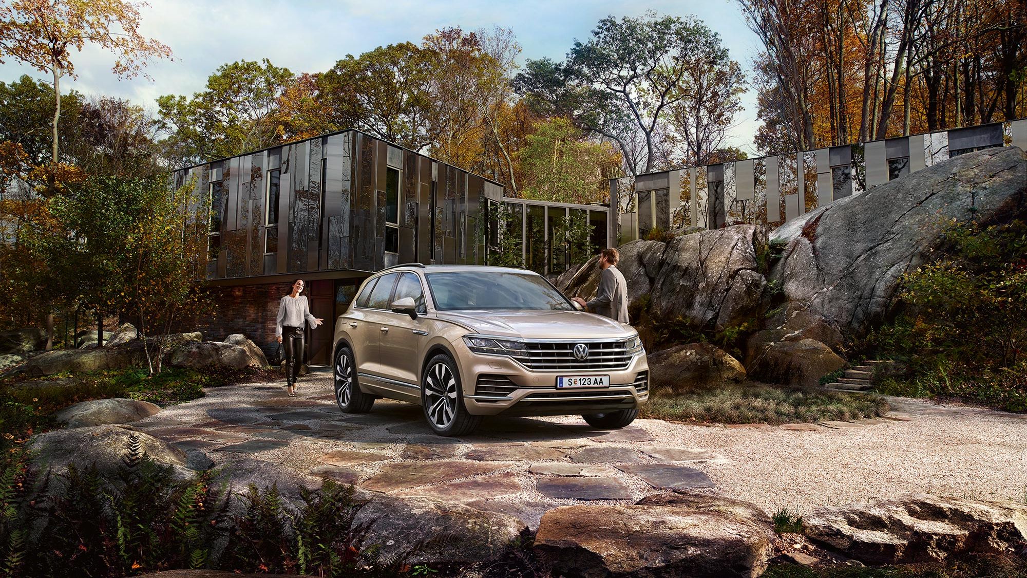 Ein VW Touareg steht geparkt in einer Einfahrt vor einem Haus, umgeben von großen Steinen 