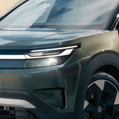 Ein grüner VW ID. Cross steht vor einem modernen Glasgebäude auf einer Betonfläche.