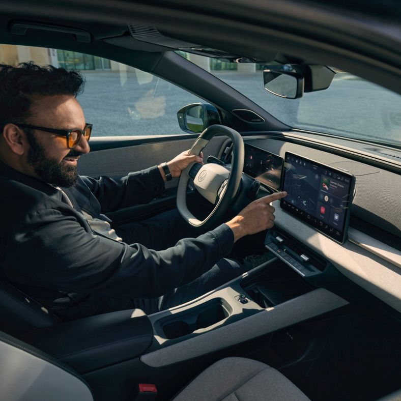 Ein Mann sitzt im VW ID. Cross und bedient das Infotainment- System.