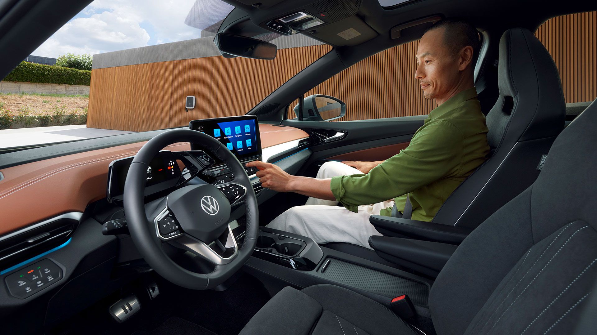 Vedere laterală a scaunelor din față ale unui VW ID.5, cu un bărbat care operează sistemul Infotainment de pe scaunul din față