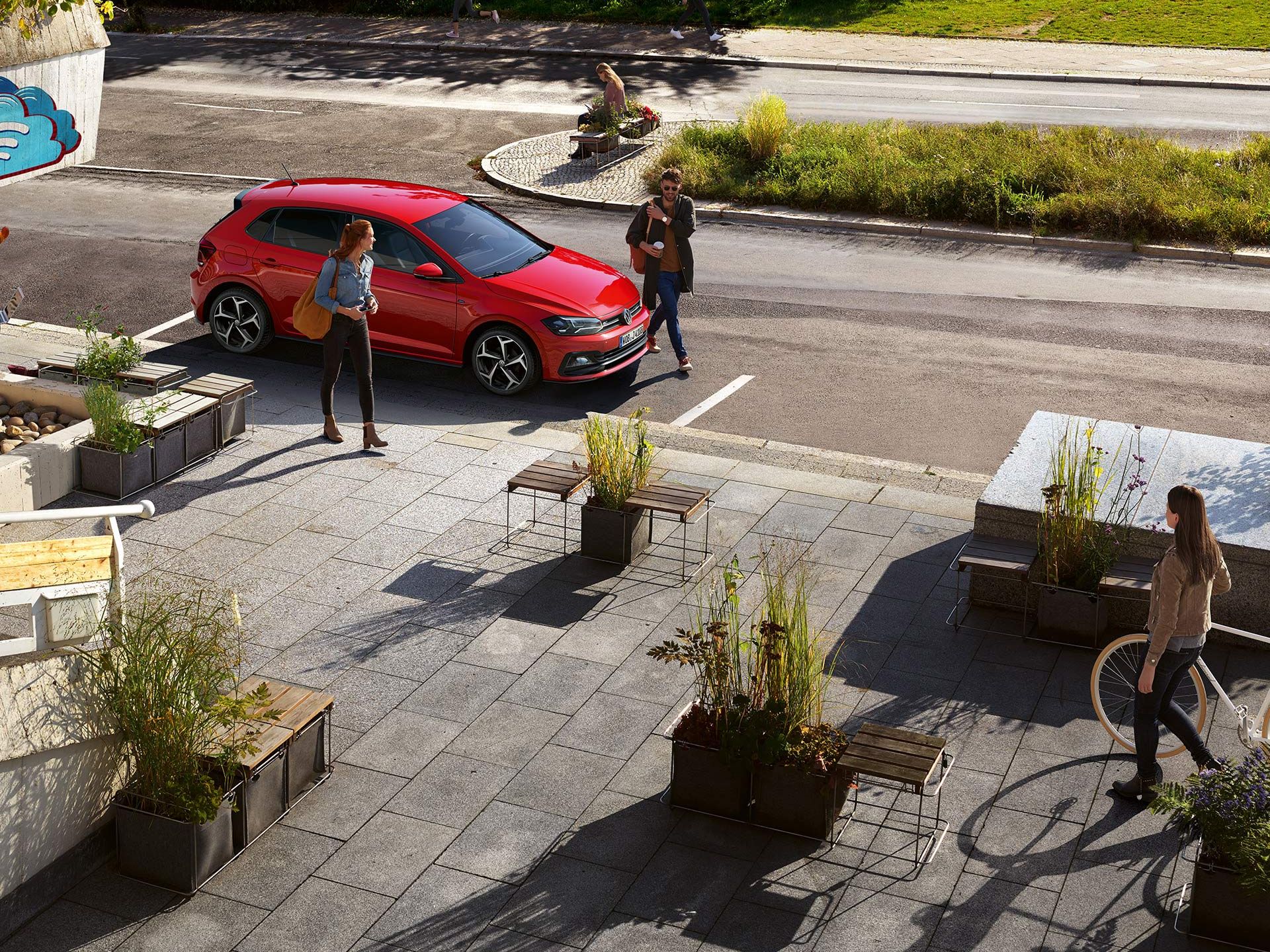 Parkender VW vor einem Platz, zwei Leute am Auto