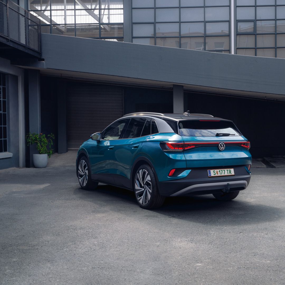 Blauer VW ID.4 in Heckansicht parkt im Innenhof eines industriellen Gebäudes.