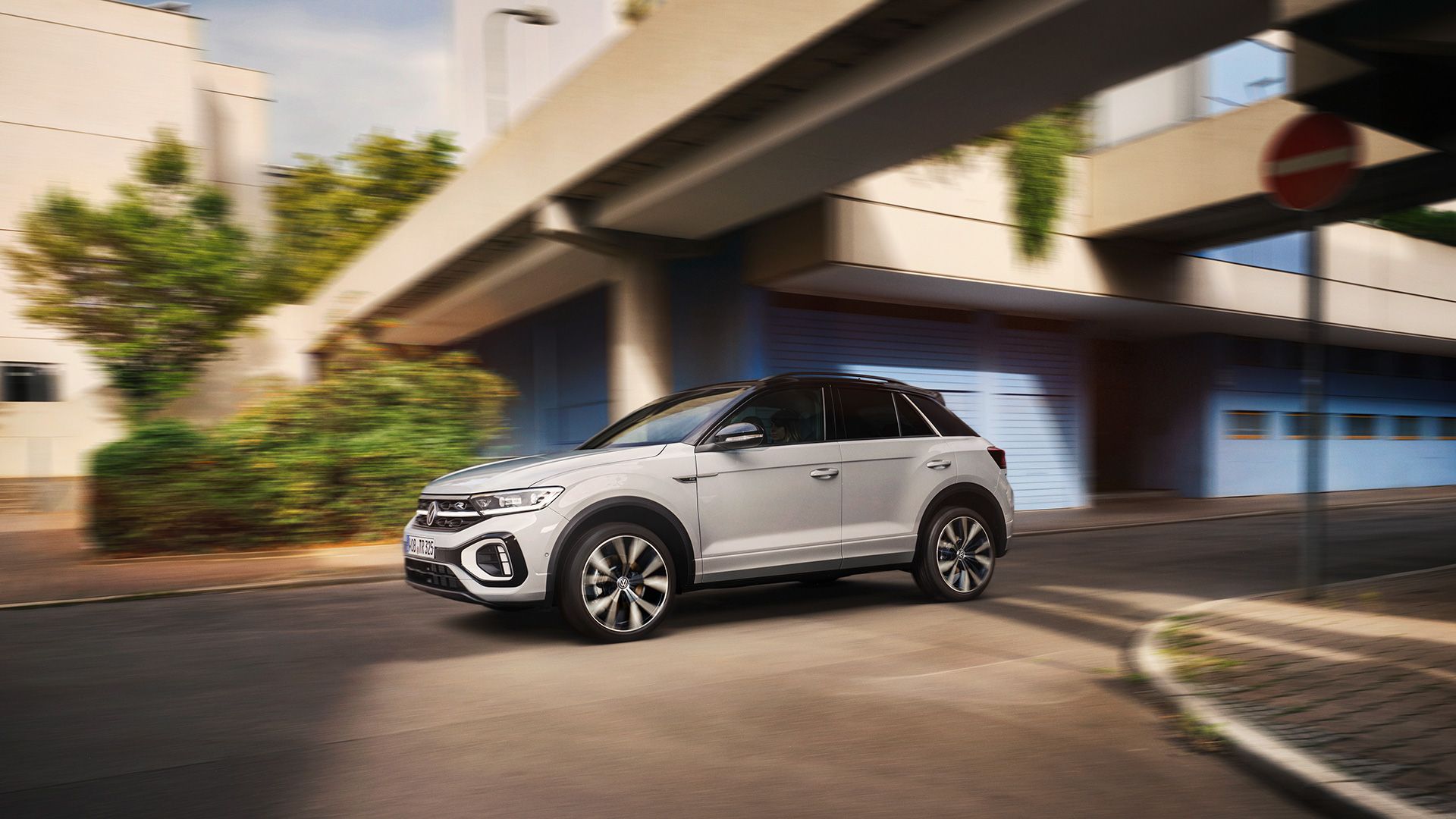 VW T-Roc R-Line de culoare albă trece dinamic printr-o intersecție, vedere din lateral