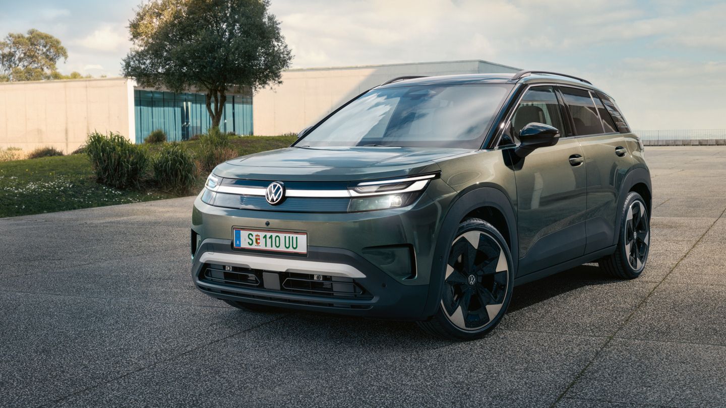 Ein grüner VW ID. Cross steht vor einem modernen Glasgebäude auf einer Betonfläche.