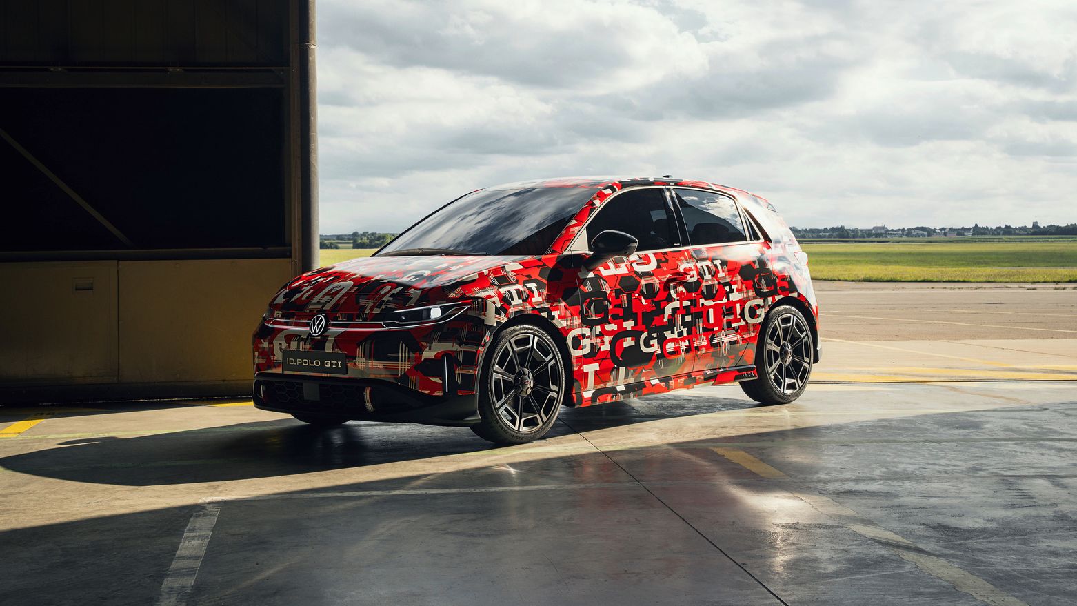 Un ID. Polo GTI, vopsit cu modele de camuflaj, este parcat într-un garaj deschis. Cerul din fundal este înnorat. Vopsirea ar putea indica un model nou sau o versiune de test.