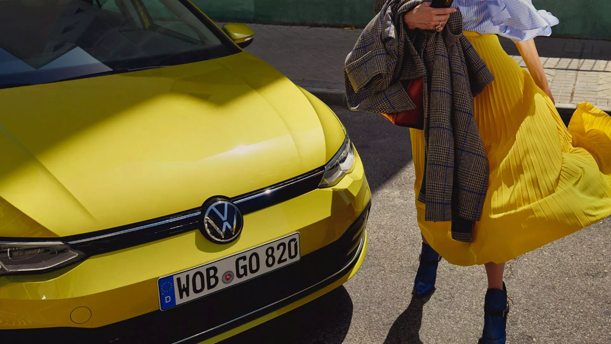 Frau steht vor VW Golf 